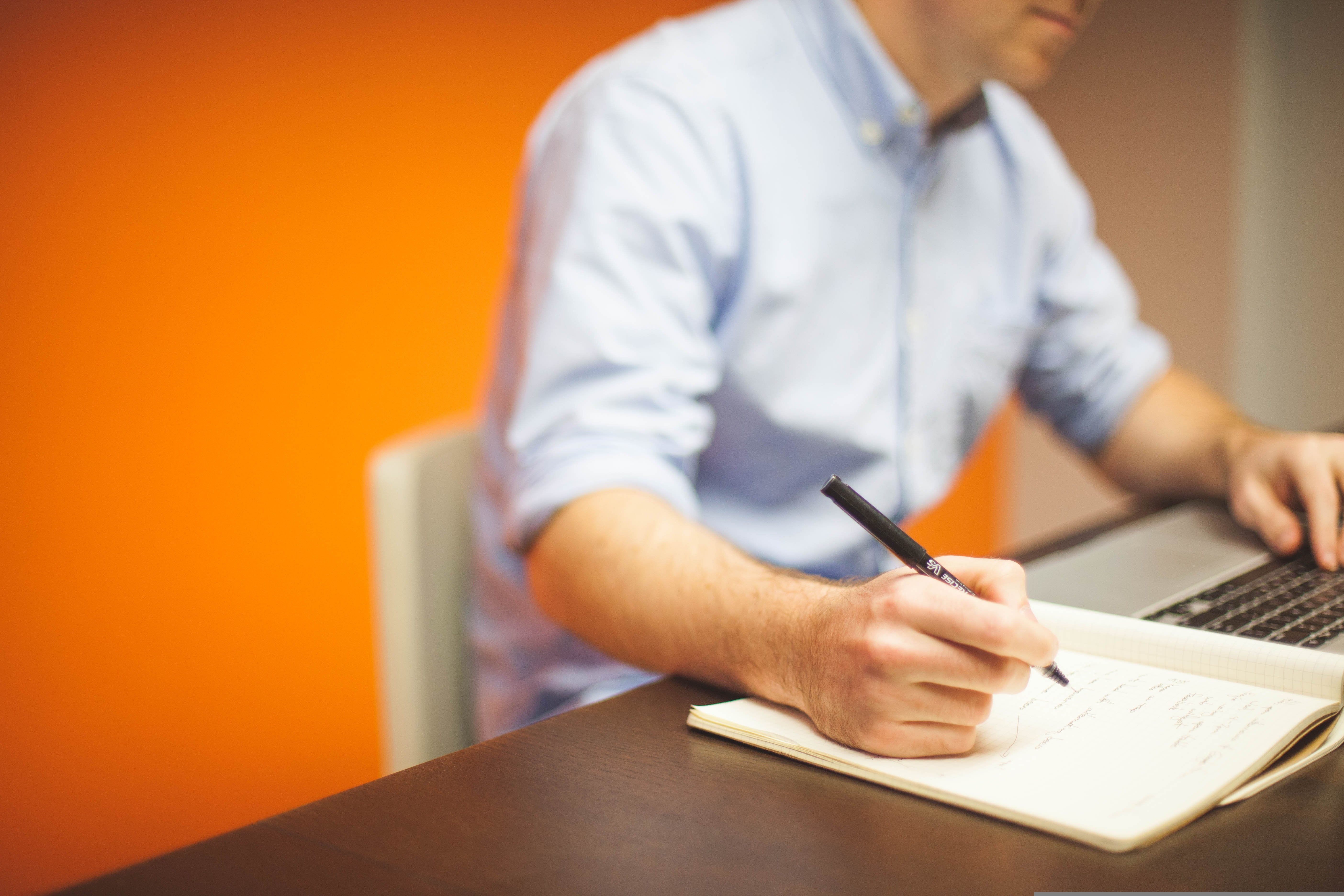 A man sitted on a chair as he researches on a laptop